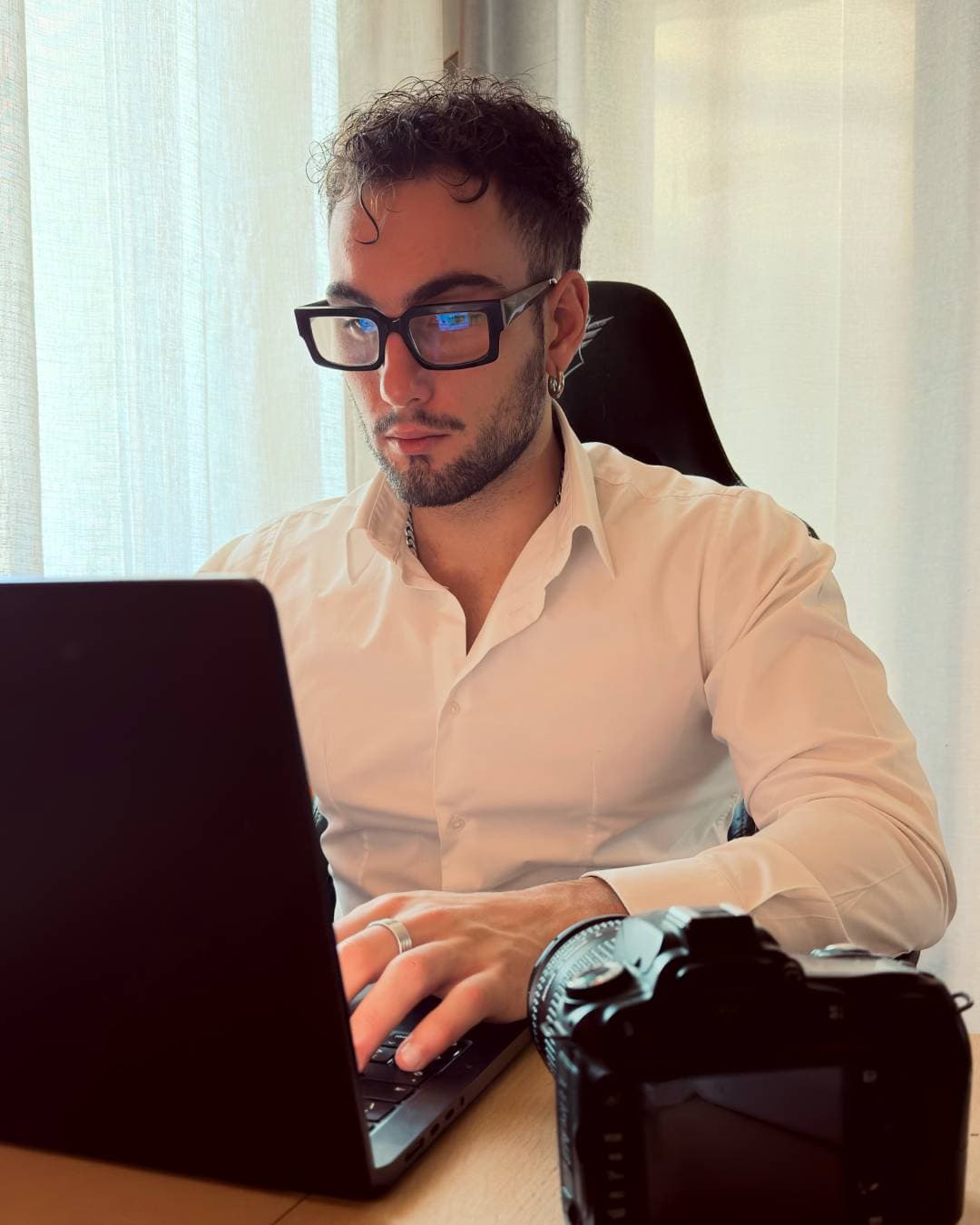 Nicolò Pano al lavoro al computer portatile, con una fotocamera reflex sul tavolo